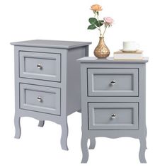 two gray nightstands with flowers and a cup on the table next to each other