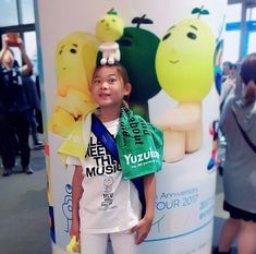 a young boy standing in front of a poster