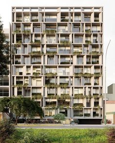 an apartment building with many windows and plants on the balconies in front of it