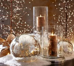 some glass vases filled with candles and snow