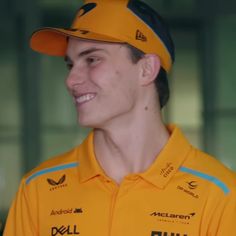 a young man in a yellow shirt and hat smiles at the camera while wearing a baseball cap