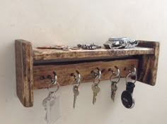 a wooden shelf with keys hanging from it's sides and several key hooks attached to the wall