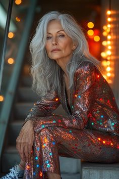 an older woman with white hair sitting on the steps in front of some christmas lights