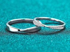 two wedding rings sitting on top of a blue surface with sparkles around the edges