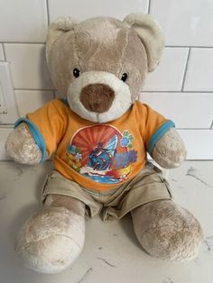 a brown teddy bear sitting on top of a white tile floor next to a wall