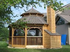 a wooden gazebo sitting on top of a lush green field