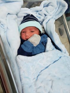 a baby in a crib with a blanket on it's head and wearing a hat