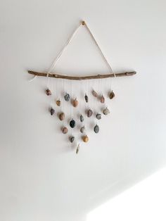 a wall hanging made out of rocks and sticks with some beads attached to the strings