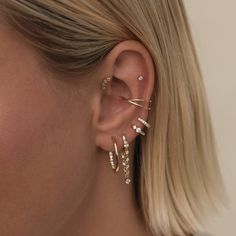 a woman wearing three different ear piercings on her left ear and the other two are gold