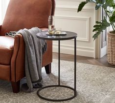 a living room with a chair, table and potted plant on the floor next to it