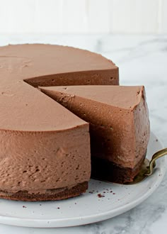 a chocolate cake on a white plate with a slice missing