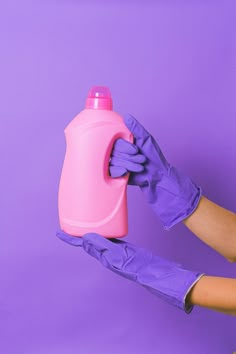 a person in purple gloves holding a pink bottle