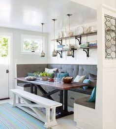 a kitchen with a bench, table and shelves on the wall next to an open door