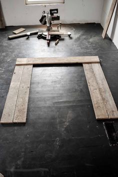 an empty room with some tools laying on the floor and one piece of wood in front of it