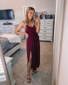 a woman is taking a selfie in her bedroom wearing a purple dress and heels