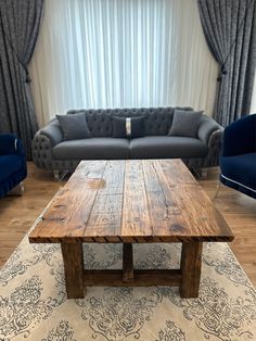 a living room with couches and a wooden table in front of a large window