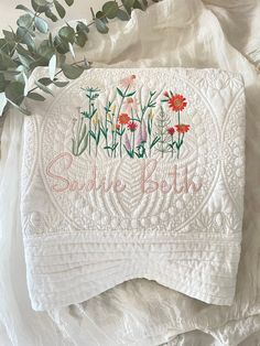 a white quilt with red flowers on it and the words sudie book written in cursive font