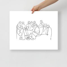 a person holding up a paper with a drawing of people sitting in front of them