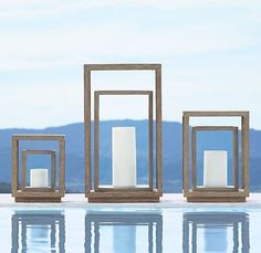 three wooden frames sitting on top of a pool next to each other with candles in them