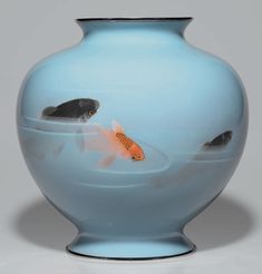 two goldfish in a blue vase with water on the bottom and one fish swimming inside