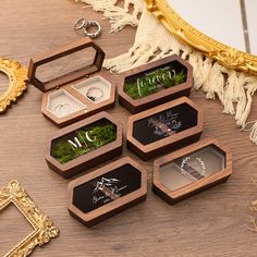 six wooden boxes with wedding rings in them on a table next to other jewelry items