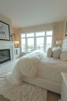 a large white bed sitting in a bedroom next to a fire place and a window