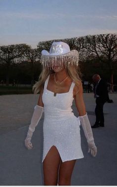 a woman in a white dress and hat is walking down the street with her legs spread out