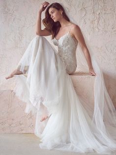 a woman in a wedding dress leaning against a wall with her hand on her head