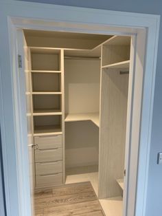 an empty walk in closet with white shelves and doors open to reveal the room's wood flooring