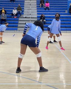 several women playing volleyball on a court with people watching from the bleachers behind them