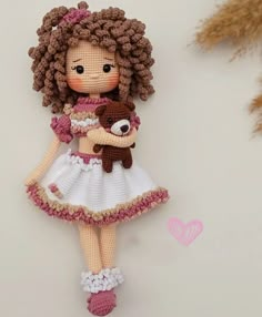 a crocheted doll holding a teddy bear hanging from a tree ornament