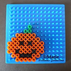 an orange and black beaded pumpkin on a blue background with the words marre written in green