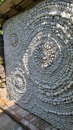 a stone wall with circles and spirals made out of rocks on the side of it