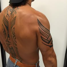 the back of a man with tattoos on his upper and lower half, standing in front of a mirror