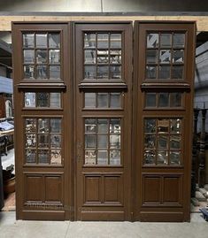 two wooden doors with glass panes on each side in a room filled with other items