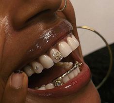 a close up of a person with braces on their teeth and gold piercings