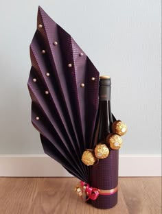 a bottle of wine and some chocolates in a purple paper fan on a wooden floor