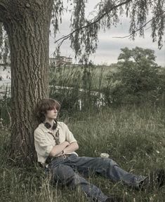 a man sitting in the grass next to a tree