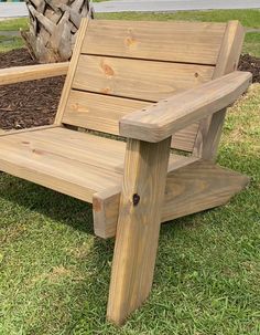 a wooden bench sitting on top of a lush green grass covered park field next to a tree