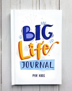 the big life journal for kids sits on a white wooden wall with blue and orange lettering