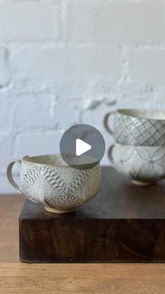 two white bowls sitting on top of a wooden table next to each other and one is holding