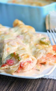 a white plate topped with lasagna covered in cheese and veggies next to a fork