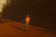 a woman is walking down the road in the dark