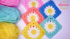 four crocheted squares with flowers on them next to balls of thread and yarn