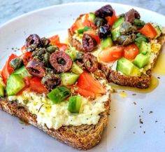 two pieces of bread with vegetables and olives on them