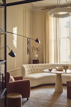 a living room filled with lots of furniture next to a large window covered in curtains