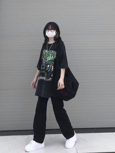 a woman wearing a face mask while walking down the street in front of a garage door