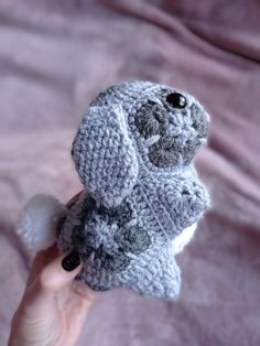 a hand holding a gray knitted stuffed animal