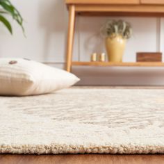 a white rug on the floor in front of a wooden shelf and potted plant