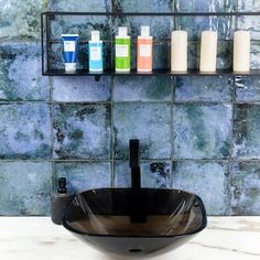 a black bowl sink sitting on top of a counter next to a shelf filled with bottles